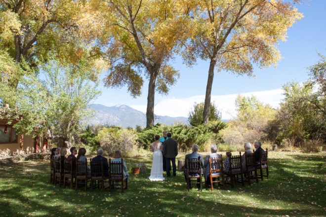 Small micro-wedding outside under yellow cottonwood trees with Taos mountain