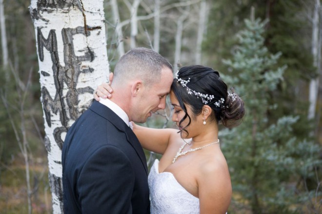 The newlyweds stand next to an aspen, conifers adorn the background