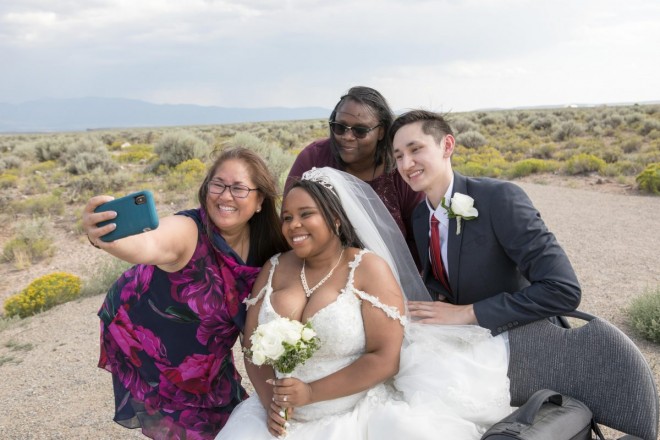 The newlyweds smiles for a selfie with their moms after their afternoon July wedding ceremony