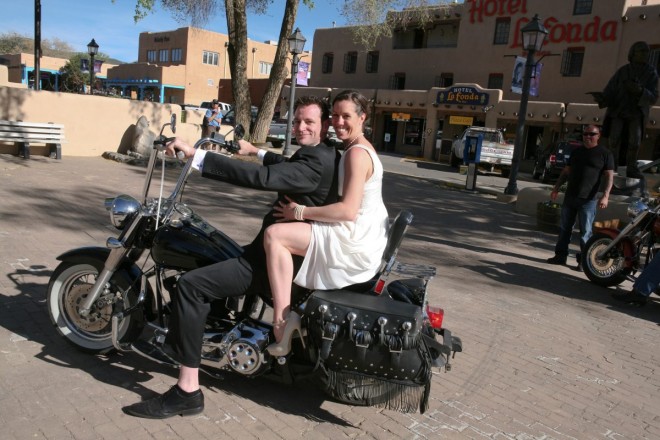 Bride and groom on a Harley in front of Hotel La Fonda on plaza in Taos