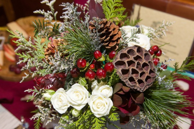 Holiday bouquet with red berries, pinecones, and white roses