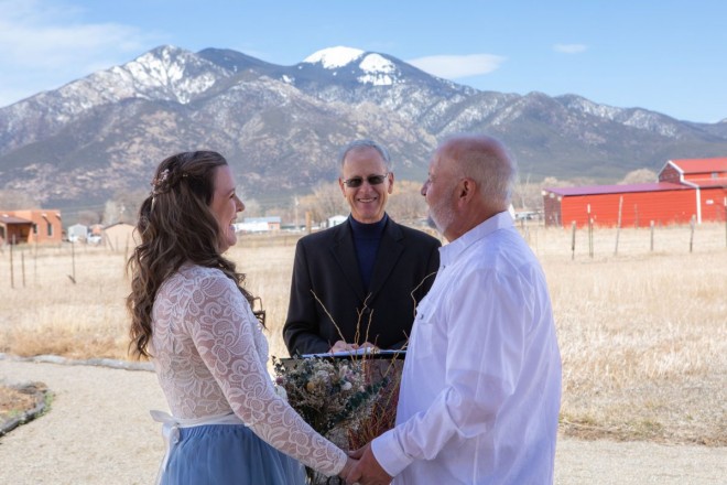 This bride and groom share a laugh with their officiant during their wedding ceremony in Taos, NM
