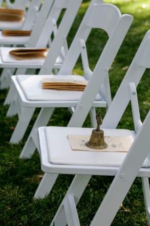 White ceremony chairs are lines up with wedding programs
