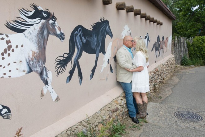 Michelle and Jeff share a kiss in front of painted horse mural on Ledoux Street in Taos, NM