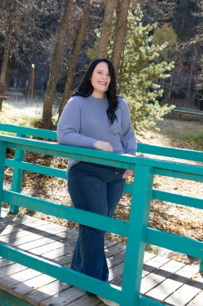 Katy's smiles and leans on a turquoise bridge during her senior photo session