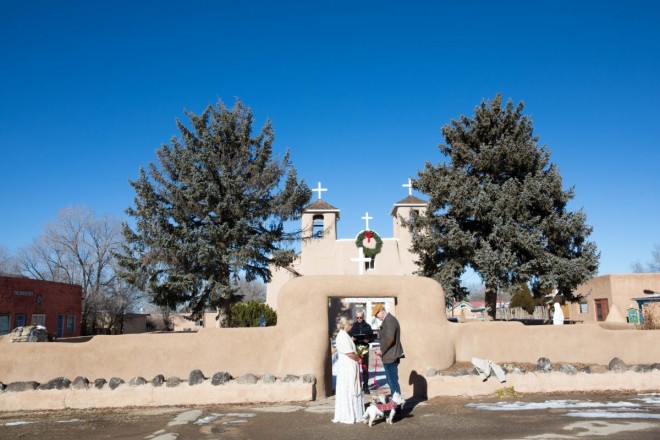 Outdoor Christmas wedding in Ranchos de Taos plaza with St Francis overlooking