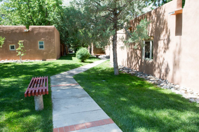 Outdoor courtyard with green grass and trees near central Taos
