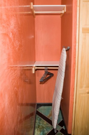 Southwest orange paint in large closet with ironing board