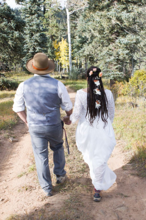 Bride and groom wearing hiking boots hike walk in Carson National Forest