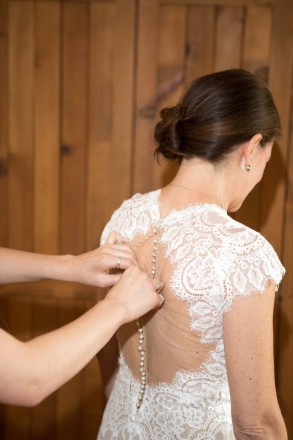 Lindsay's daughter clasps the pearl buttons on the back of her wedding dress
