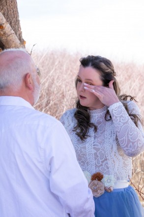 Bride in blue wipes away a tear during her Taos wedding ceremony