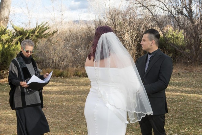Maya's veil is lifted by the wind at their outdoor wedding.