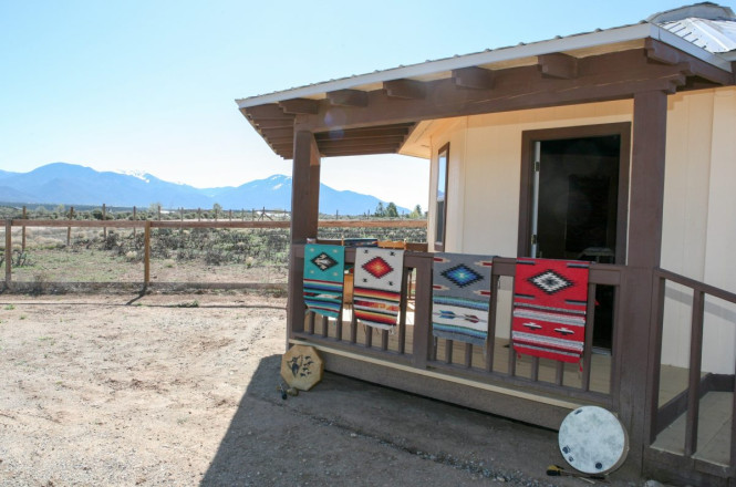 Hogan with Navajo rugs and drums with Taos mountains in background