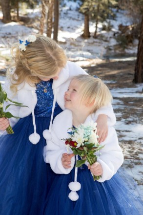 Flower girls in winter capes with bouquets