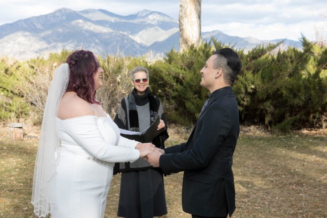 Maya and Robert hold hands in front of officiant during winter wedding.