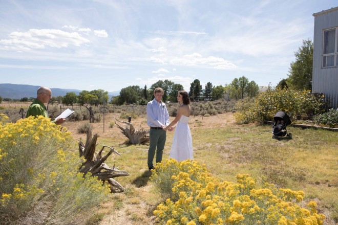 Katy and Daniel's ceremony amongst the yellow sunflowers and chamisa with their baby watching