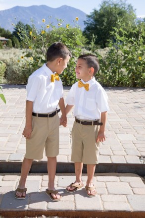 Young brothers hold hands and smile at each other during family portraits