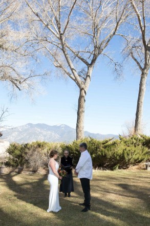 Bare cottonwoods during December wedding ceremony overlooked by Taos Mountain