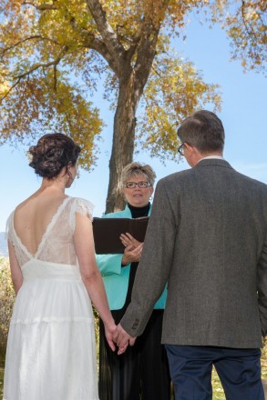 Under the golden cottonwoods, Devin and Case listen to their wedding minister