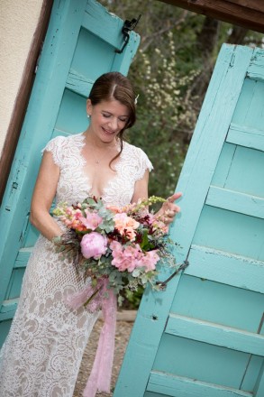 Lindsay looks at her bouquet in front of turquoise wooden doors