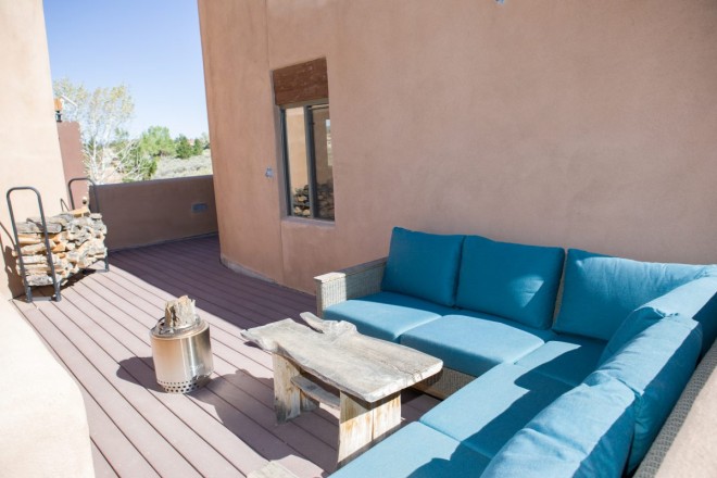 Uncovered patio with turquoise couch and firewood holder
