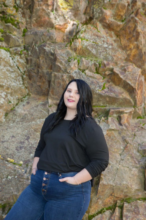 Katy stands with mossy rocks in Marlette Park for senior pictures in Red River
