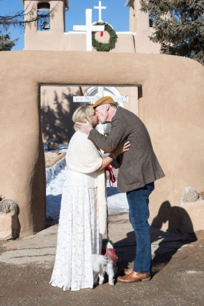 Lisa and Ian seal their vows with a kiss in front of San Francisco de Asis in Taos, NM