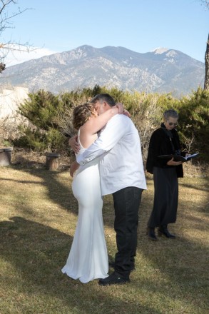 The Kiss looked on by famous Taos mountain Pueblo Peak