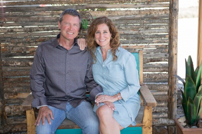 Bill and Chasity smile from their turquoise bench on their front porch in El Prado, NM