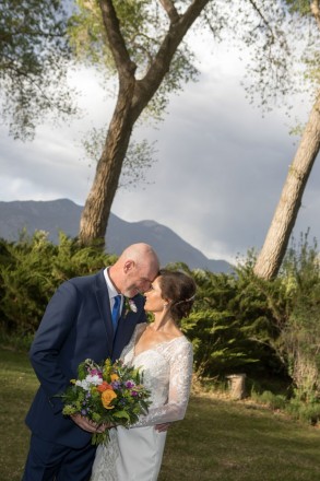Taos wedding photographer captures the sunshine kissing the bride and groom while the mountains watch