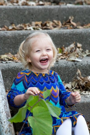 Autumn portraits of a young child on a set of stairs with leaves