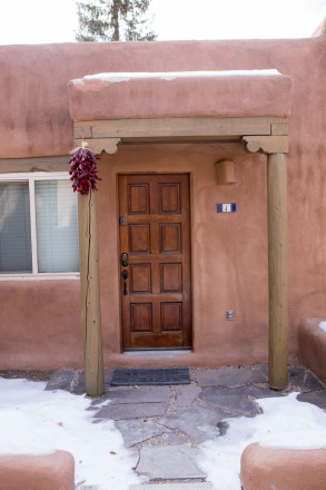 Taos pueblo style stucco apartment with chiles and Mexican tile house number