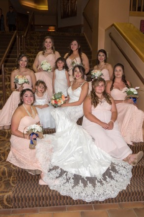 Monica and her bridesmaids sit on the stairs in the entrance of Angel Fire Resort for a photo of the bridal party.