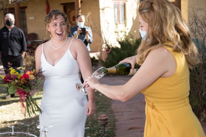Bride, Rosie looks on as her maid-of-honor pours local champagne for a toast