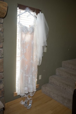 The brides dress, veil, and shoes in front of window