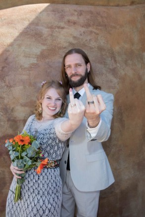 Bride and groom give the fingers, to show off their new weddings rings