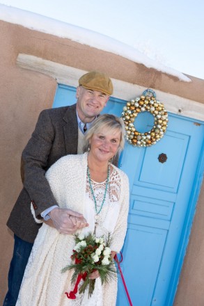 Popular Taos blue paint color with Christmas decorations, adobe, snow, and bride and groom.