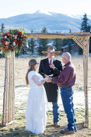 Wedding officiant wearing cowboy boots and a hat, groom wearing jeans