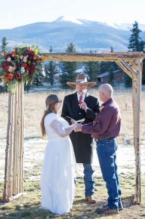 Wedding officiant wearing cowboy boots and a hat, groom wearing jeans
