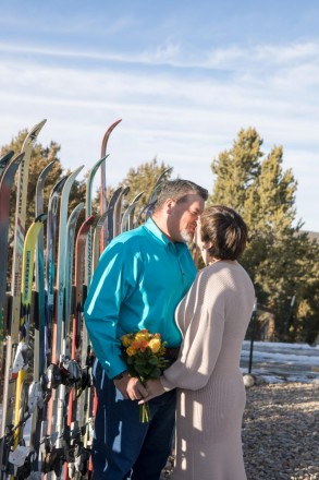 Carrie and Matt kiss in front of a fence made out of skis!