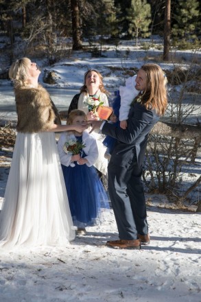 Amberly and Kyle share a laugh with their officiant at their wintertime wedding ceremony