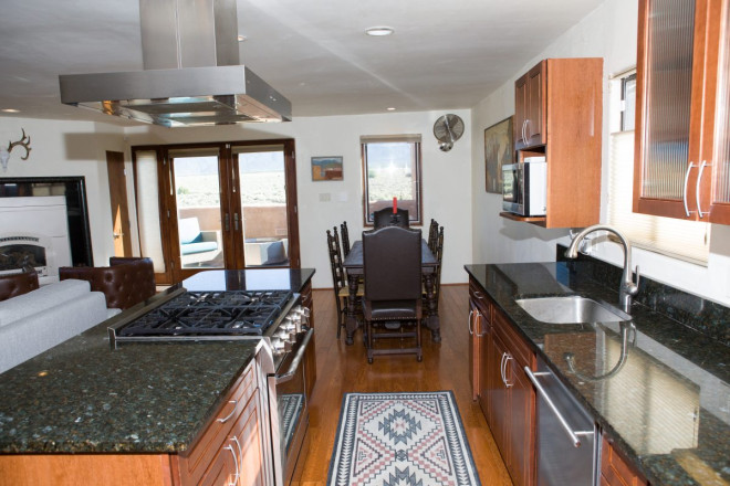 View of kitchen with granite counter and stainless steel hood