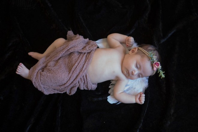 Little angel baby takes a nap during her newborn portraits