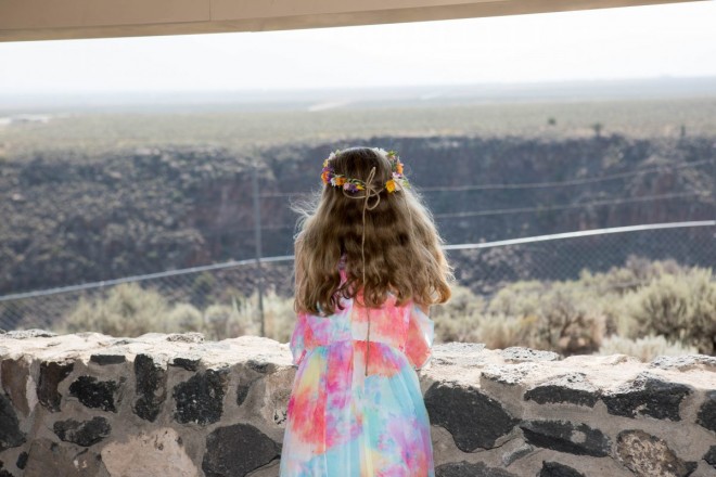 Tie Dye flower girl gazes out at the Taos gorge on wedding morning