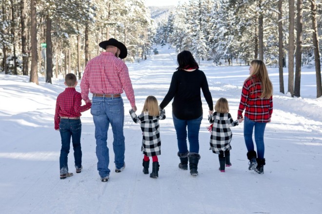 Angel Fire family has portraits in snowy scene wtih pine trees