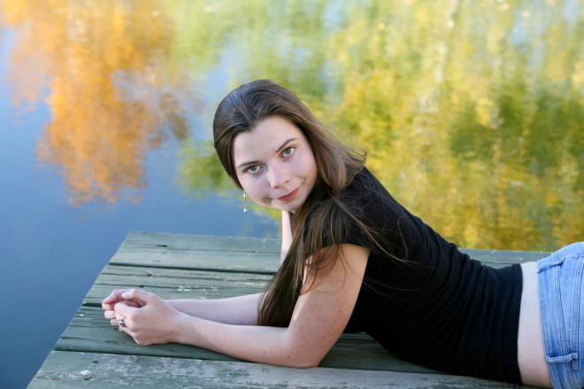 Taos High senior poses in October with reflection of autumn leaves