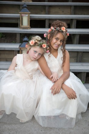 Flower girls with flower crowns and white dresses sit with lanterns before the wedding ceremony
