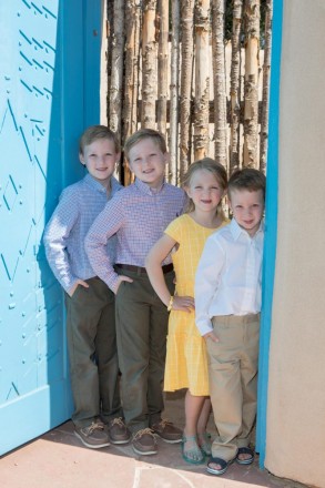 Portrait of the grandchildren with Taos-blue door and latilla fence