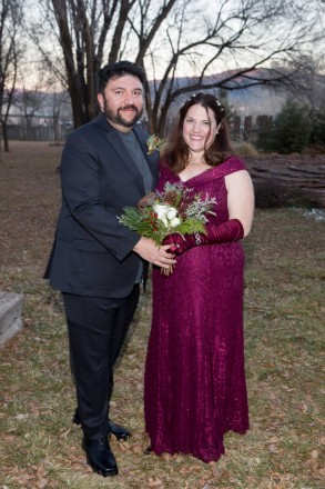 Beautiful bride and groom with winter bouquet and pink Taos mountaintops on the horizon