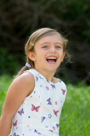 A child laughs with delight during her July portrait in red, white, and blue.